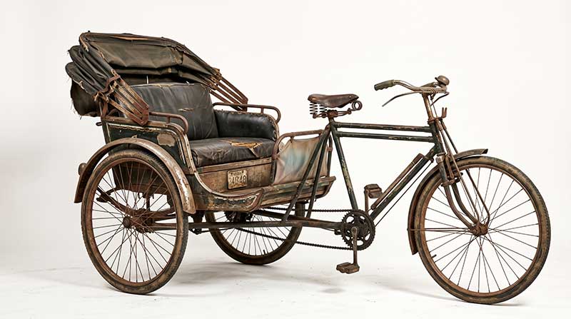 AI-generated vintage weathered dark green metal tricycle rickshaw with torn leather passenger seat and folded canvas canopy by Inspirious Design